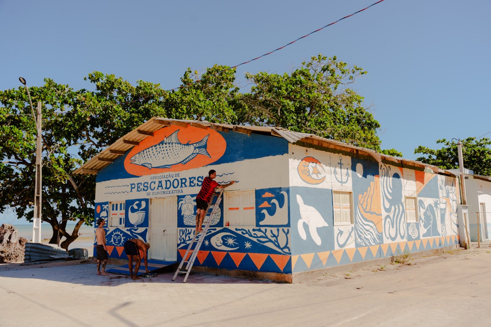Artista pintando o mural da Associação de Pescadores de Cumuruxatiba